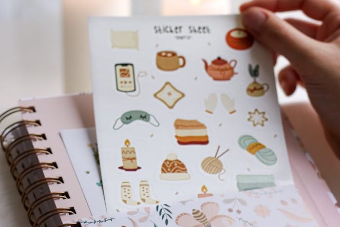Close-up of Woman Holding a Sheet with Stickers in a Pocket of a Notebook 